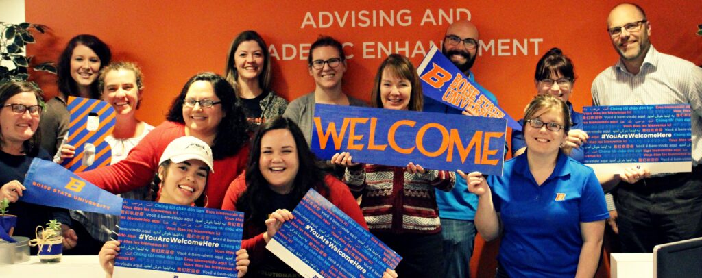 AASC staff pictured together and holding "You Are Welcome Here" signs.