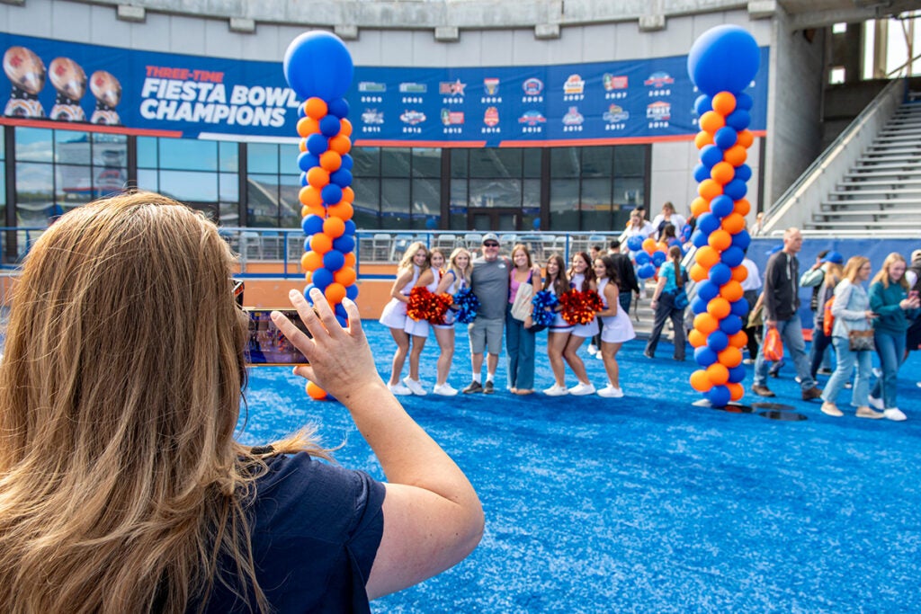 A Bronco Day visitor takes a photo of their family on the Blue Turf