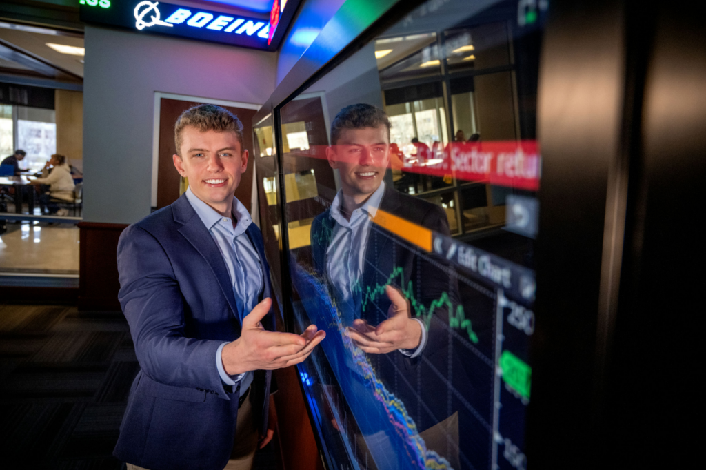 Nick Lloyd standing in front of a TV screen in the Dykman Financial Trading room.