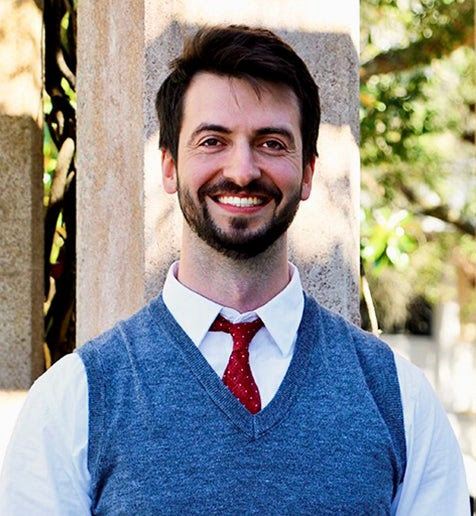 Man with blue vest, red tie, and brown hair