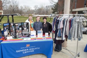 Students pose with clothes closet display on the quad
