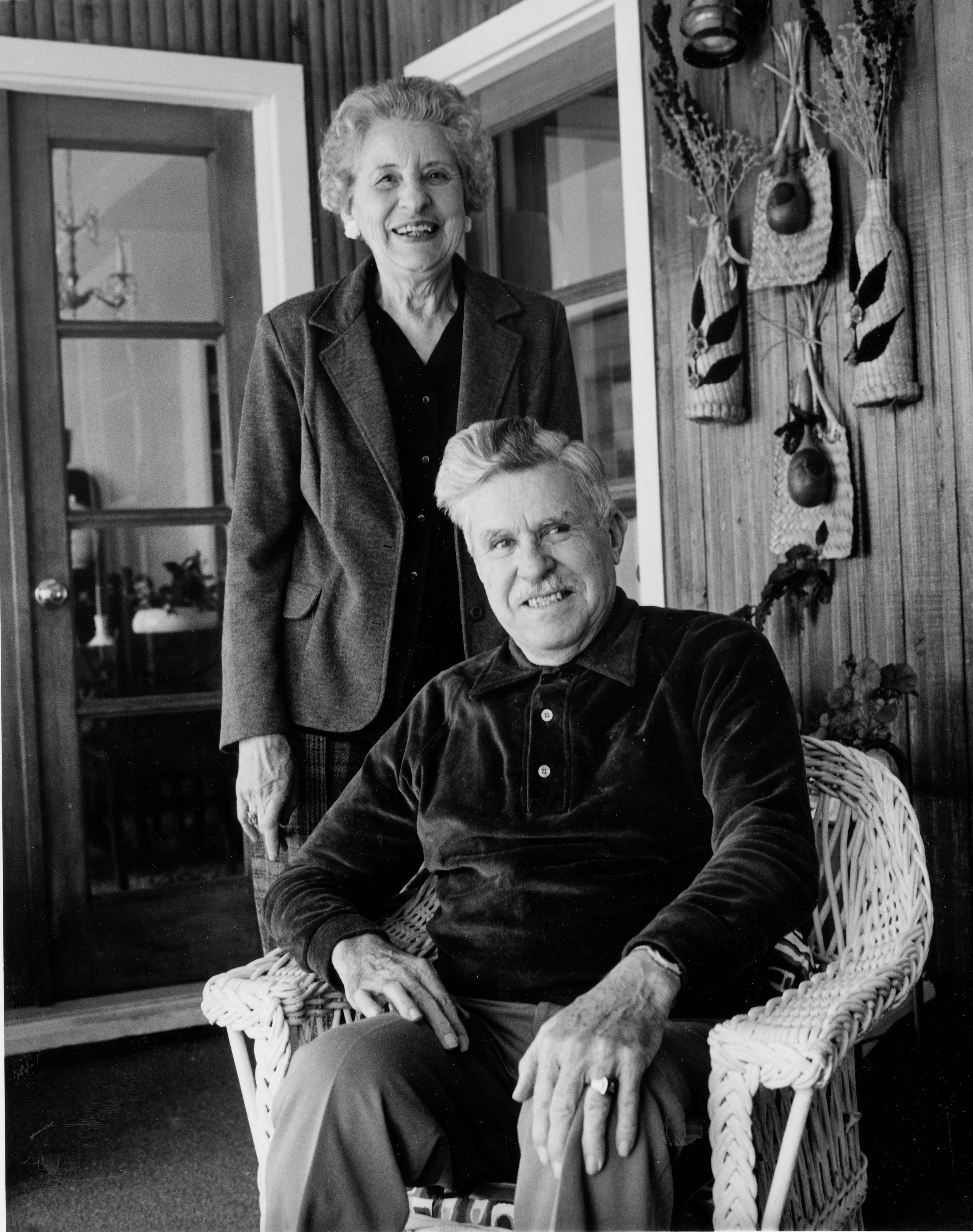 Man sitting and woman standing posing for a photo in their home
