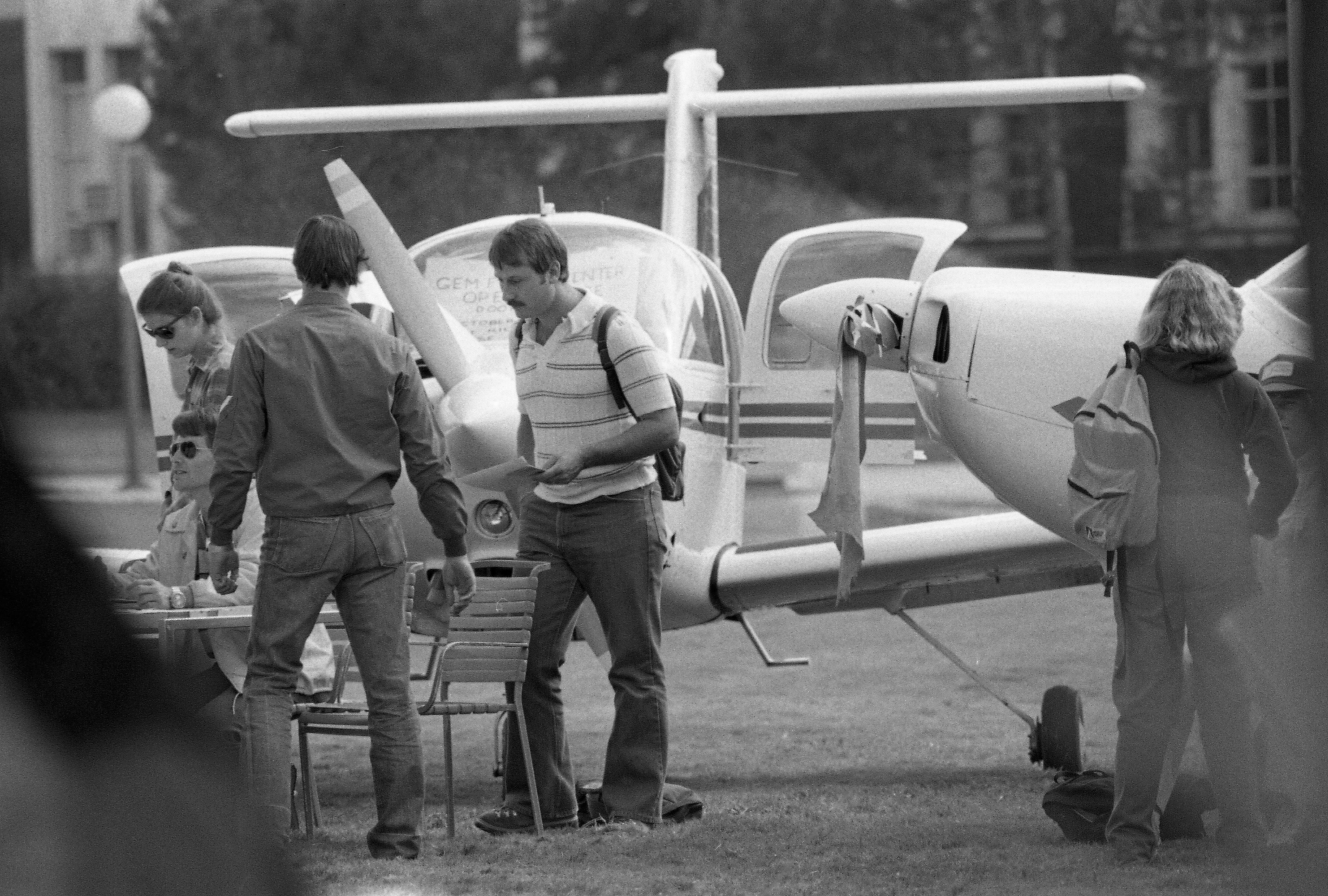 Two students examine an airplane on the university campus.