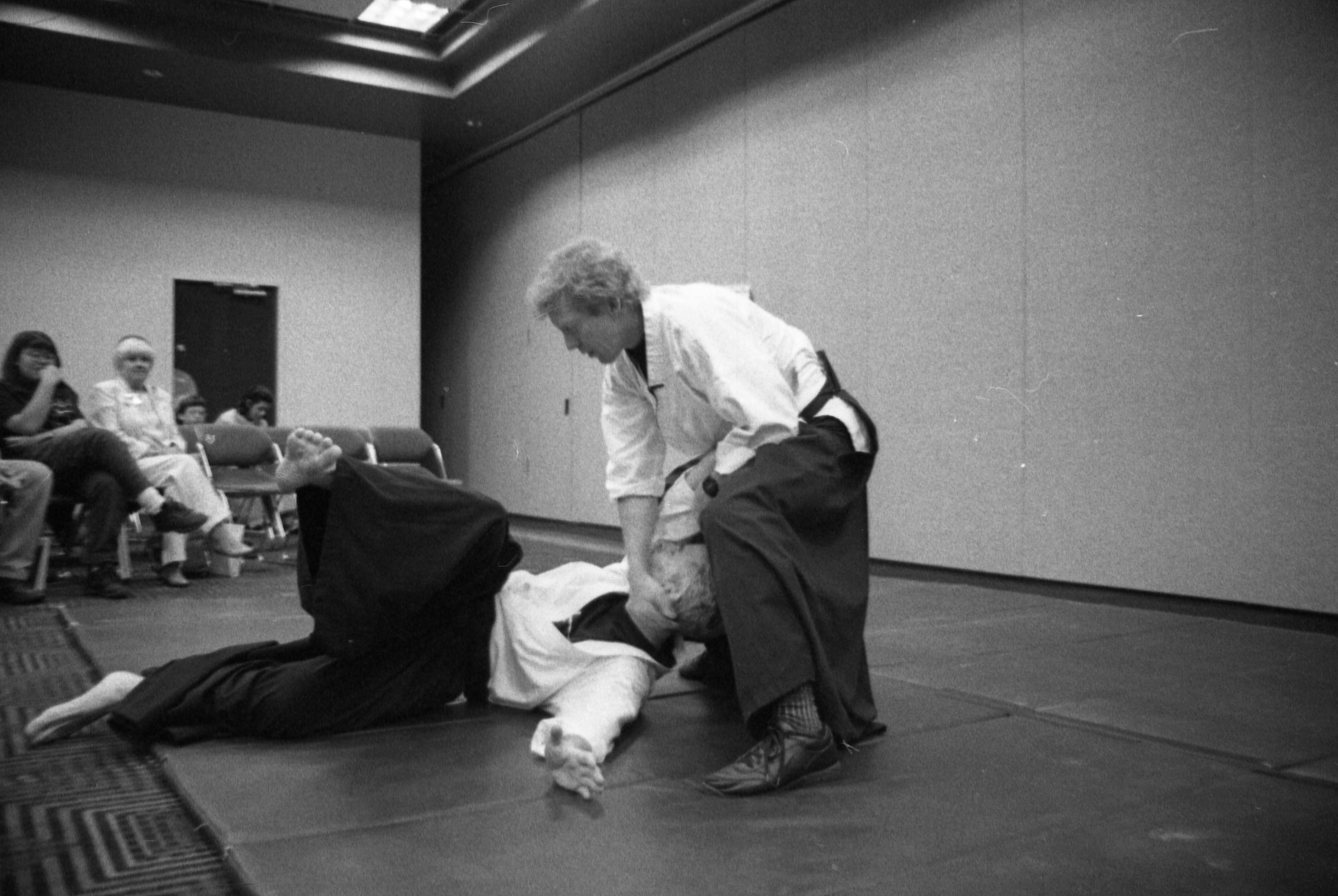While demonstrating the art of aikido, one bouts with another man; both are clothed in white shirts