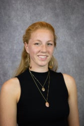 student headshot smiling standing in front of gray backdrop
