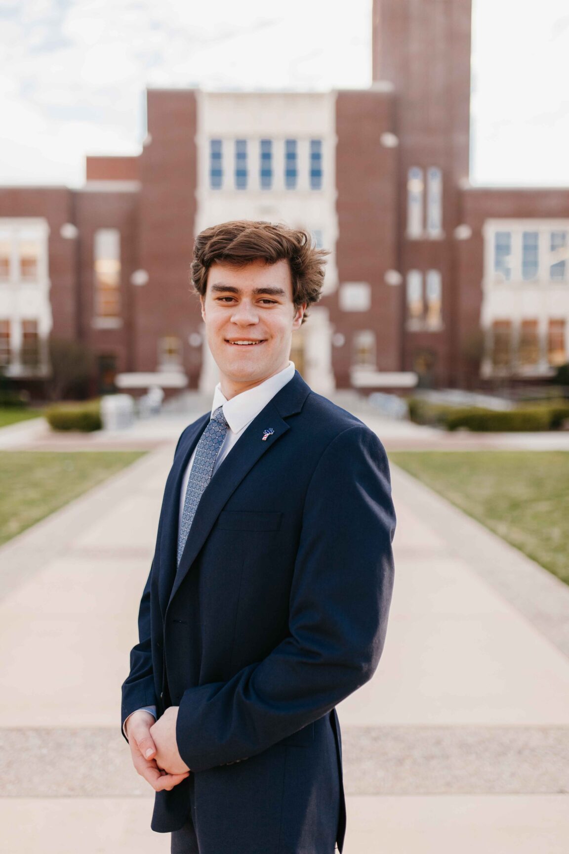 Austin Rose stands in front of a brick building smiling