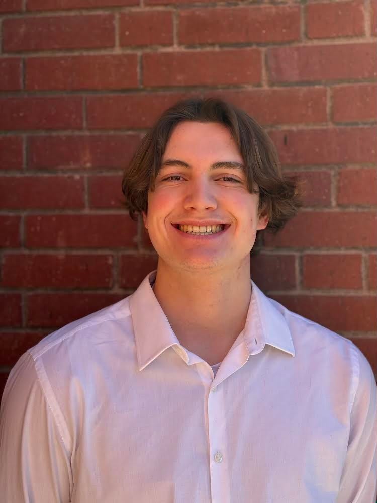 Braden Udager stands in front of a brick wall smiling