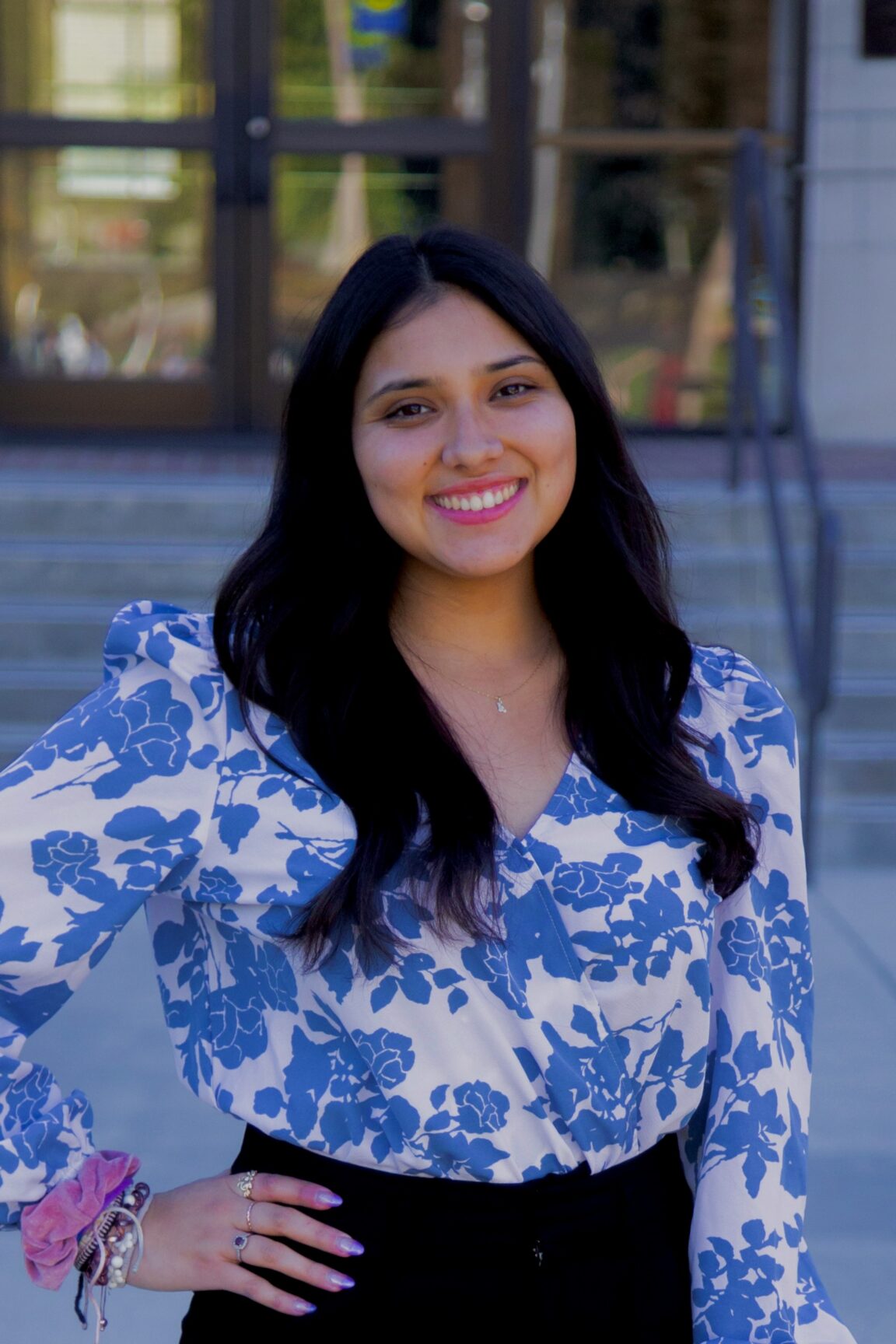 Aliese Vasquez stands on front of glass doors smiling