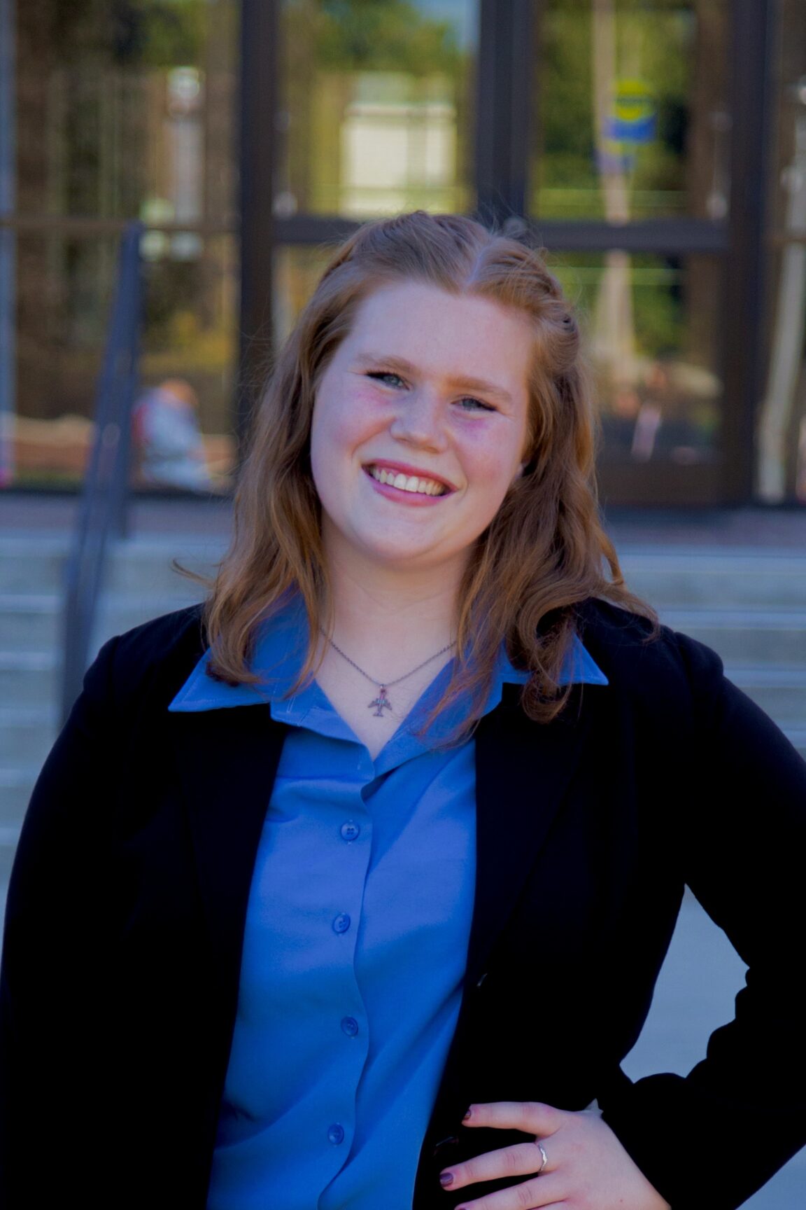 Alli Koetsier stands in front of glass doors, smiling