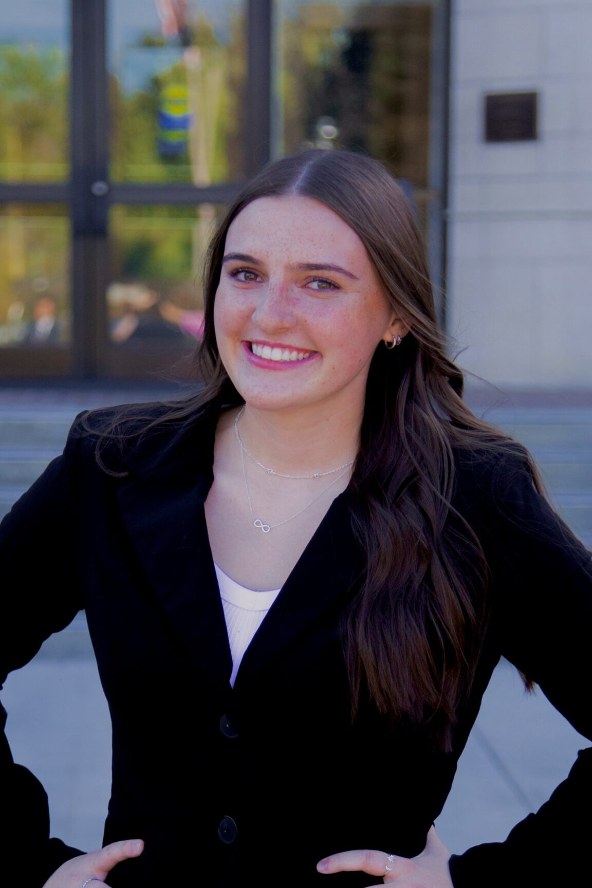 Annika Williams stands in front of glass doors, smiling with her hands at her hips