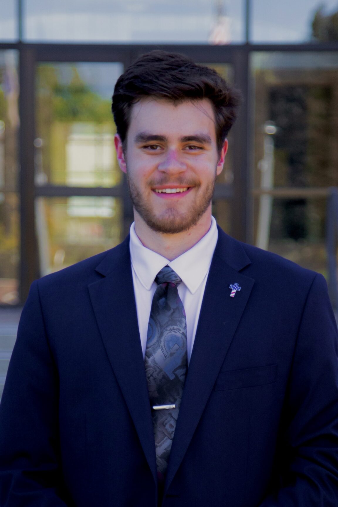 Austin Rose stands in front of glass doors, smiling