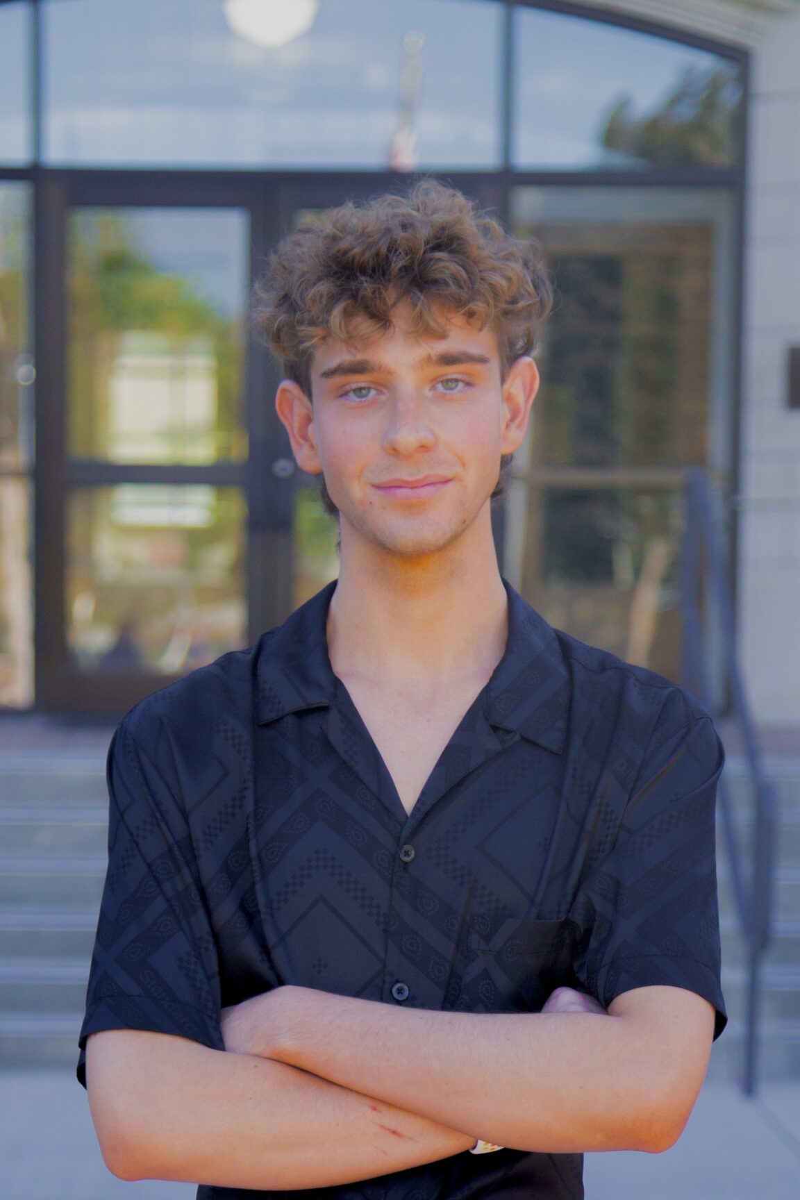 Caden Skelton stands on front of glass doors smiling