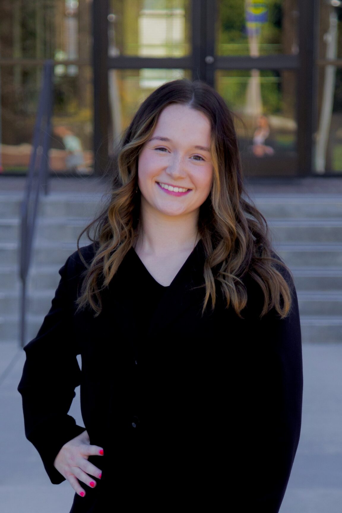 Delana Legault stands in front of glass doors, smiling