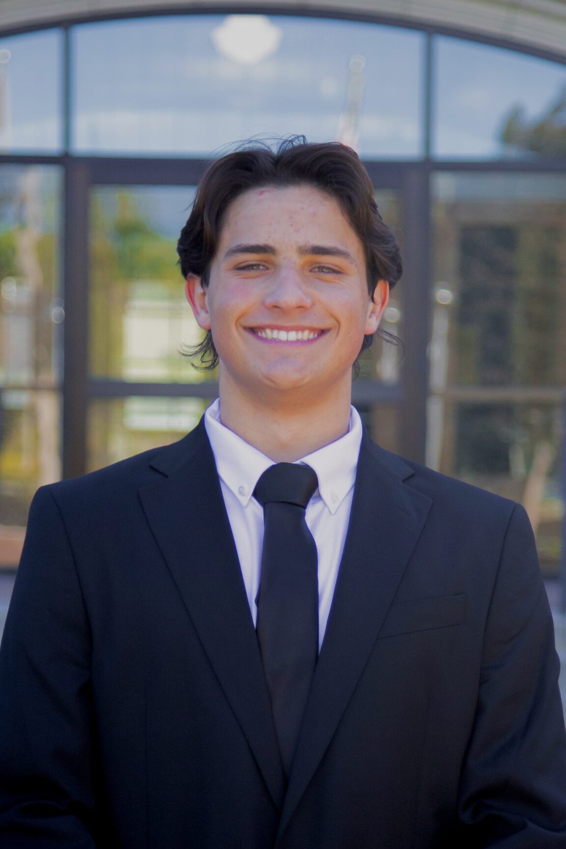 Dimitri Sydoruk stands in front of glass doors, smiling