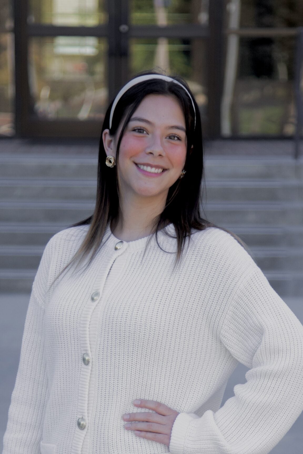 Emia Venegas stands in front of glass doors, smiling