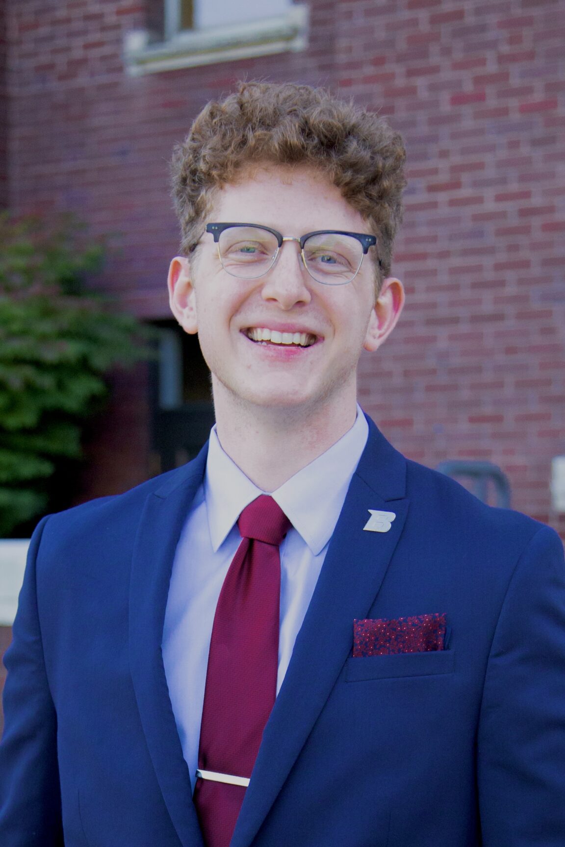 Ethan LaHaug stands in front of a brick building smiling