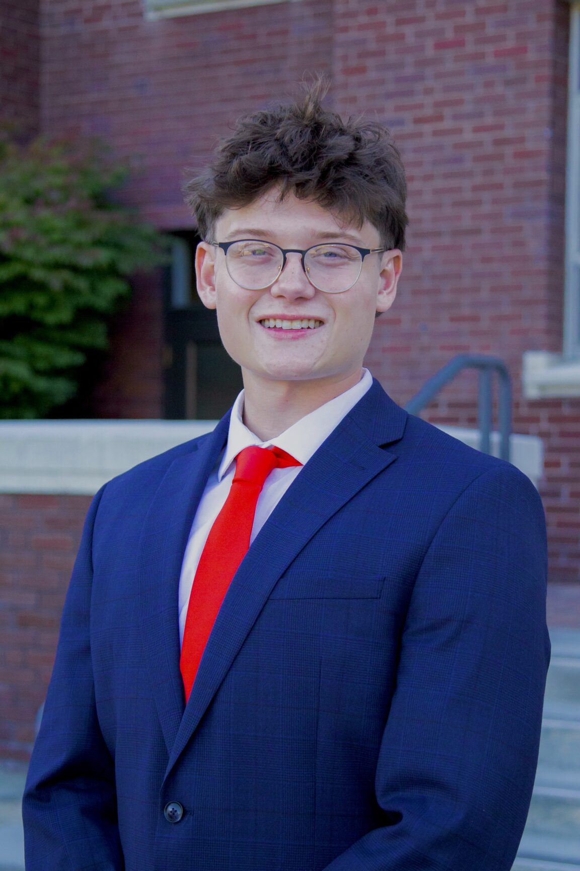 Ethan Mariner stands on front of a brick building smiling