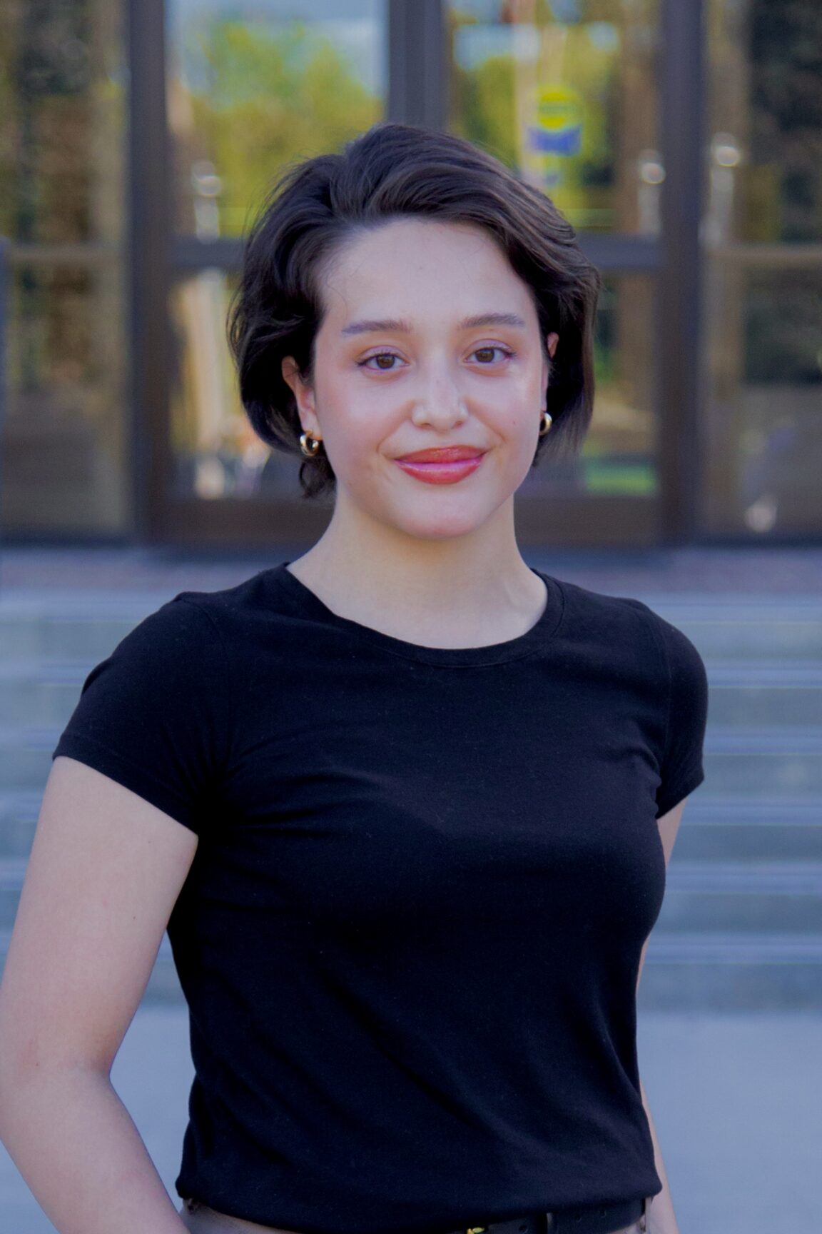 Gizelle Smith stands in front of glass doors, smiling