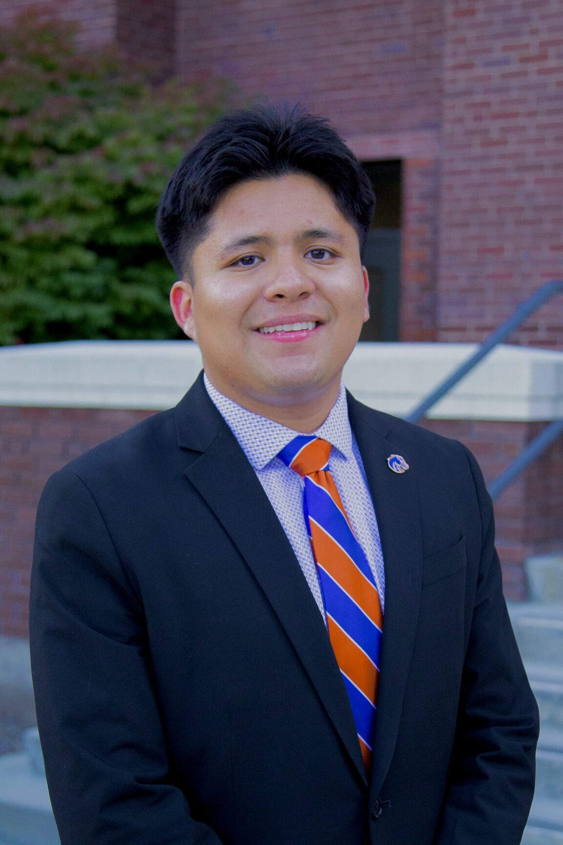 Isaac Celedon stands on front of a brick building smiling