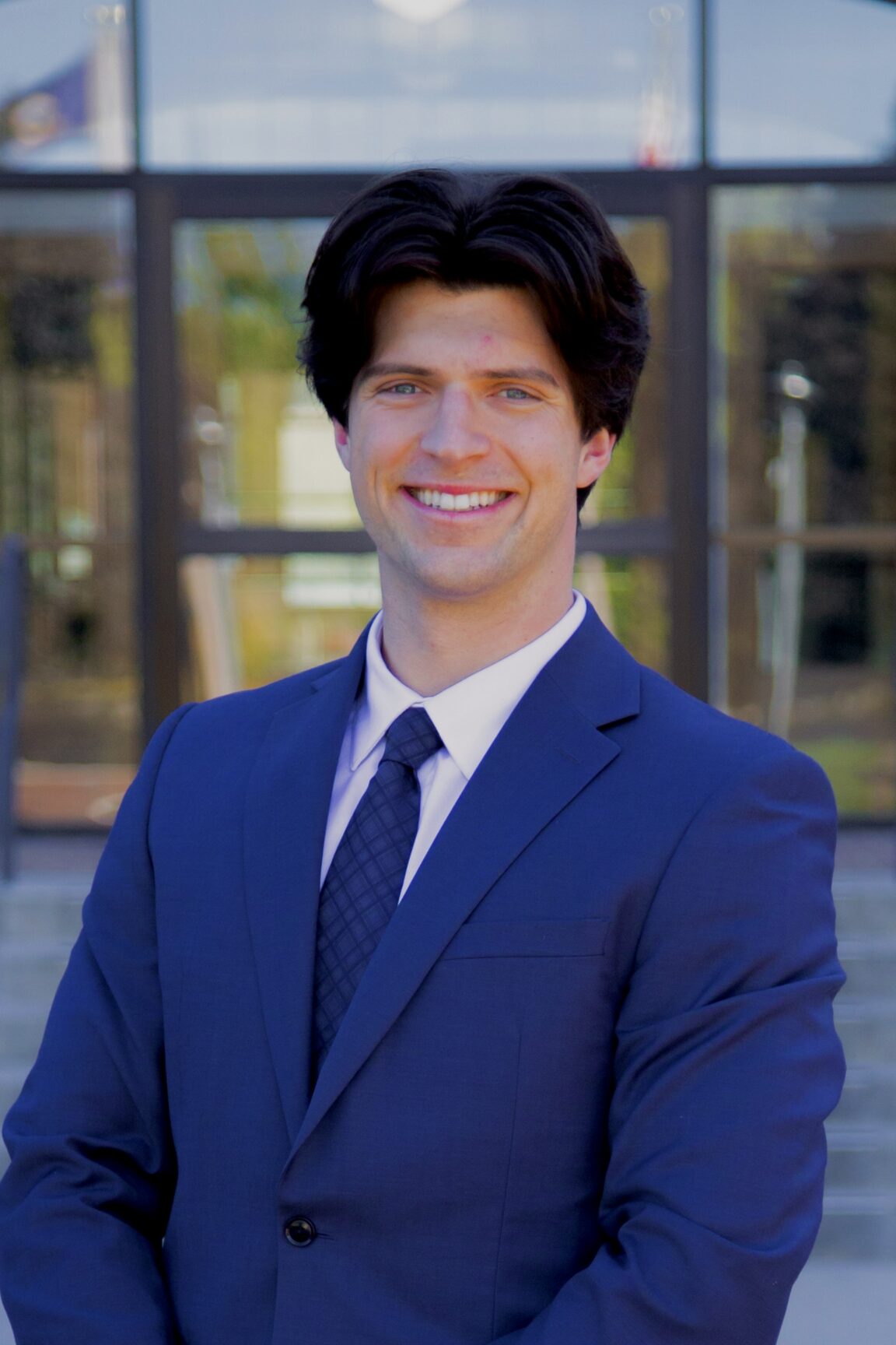 Joshua Dilts stands in front of glass doors, smiling