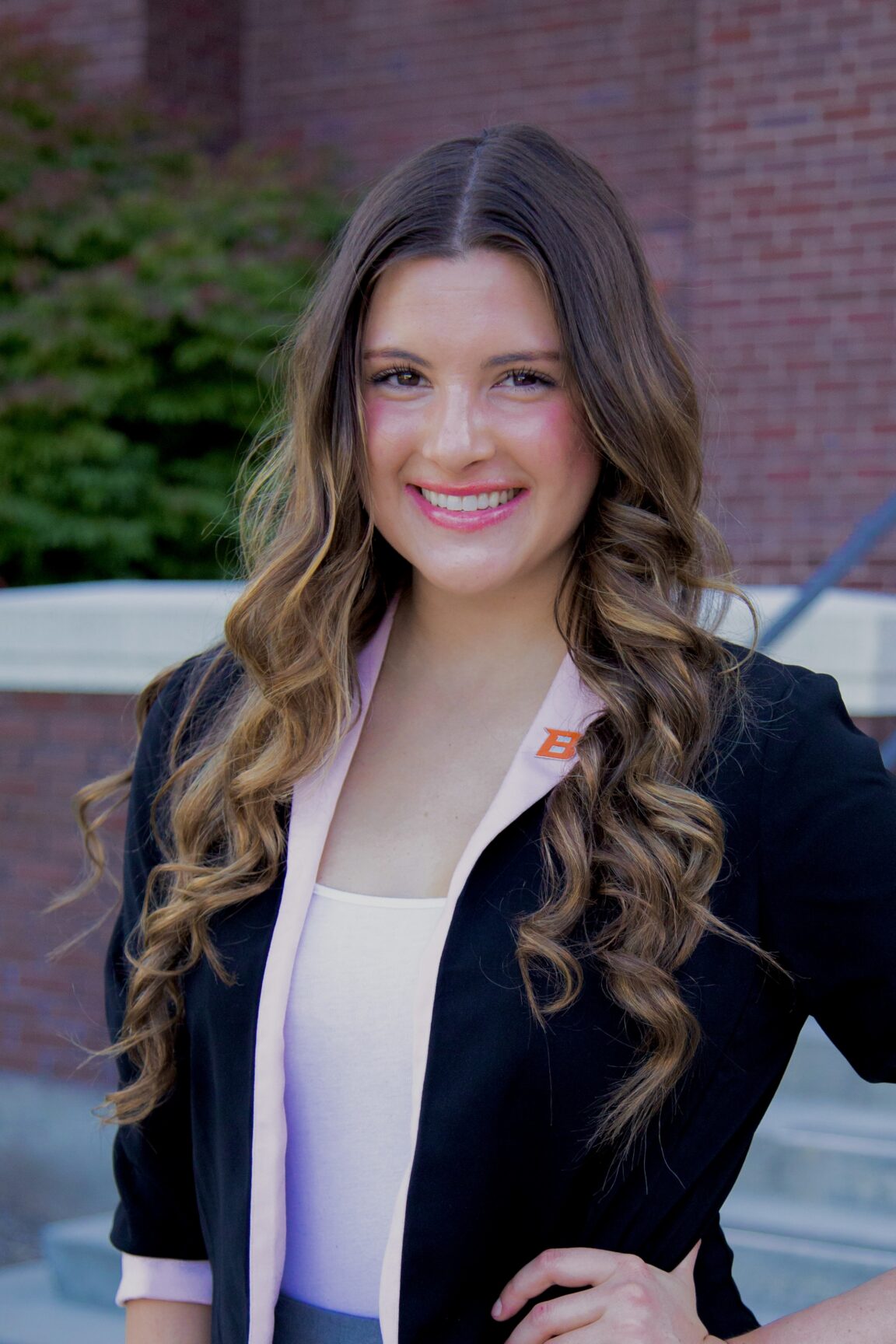 Kate Perkes stands on front of a brick building smiling