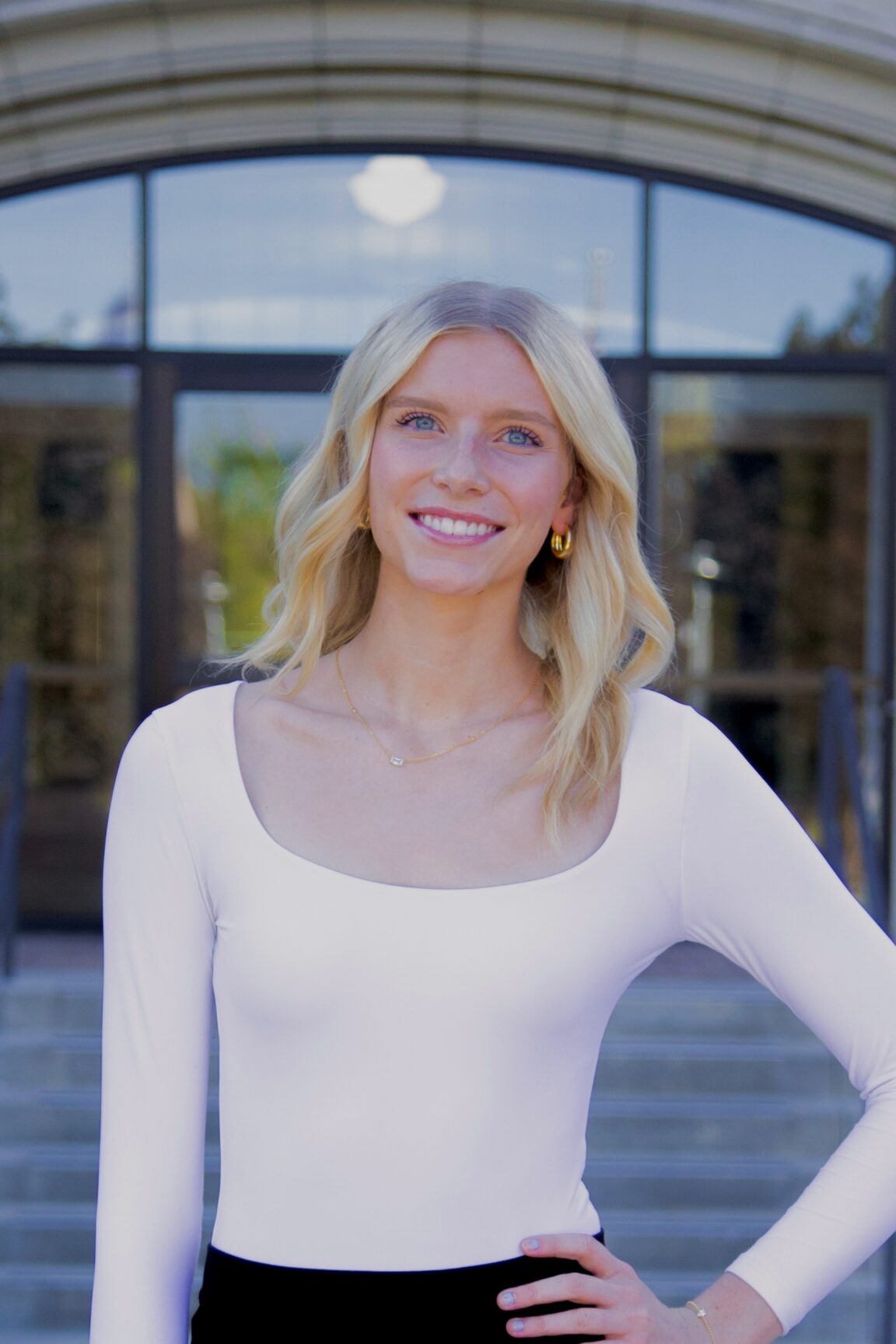 Kendall Hastings stands in front of glass doors, smiling