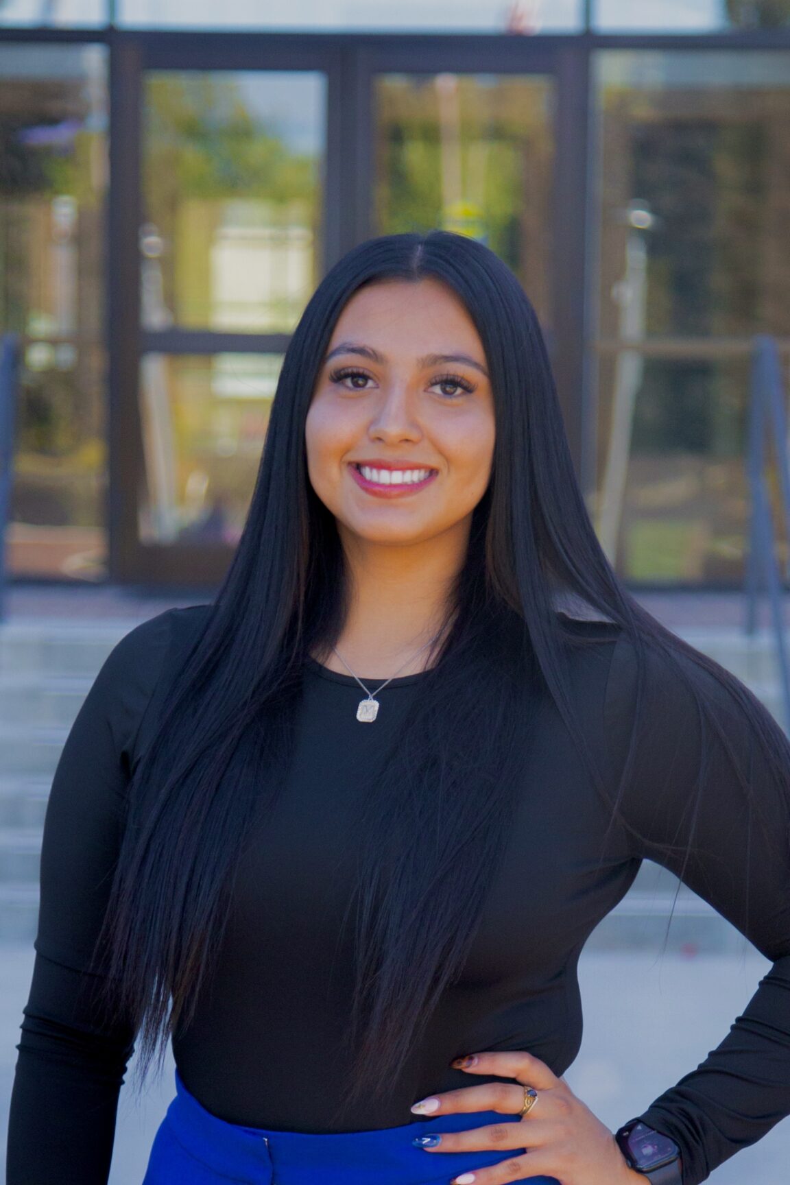 Mercedes Gomez stands in front of glass doors, smiling