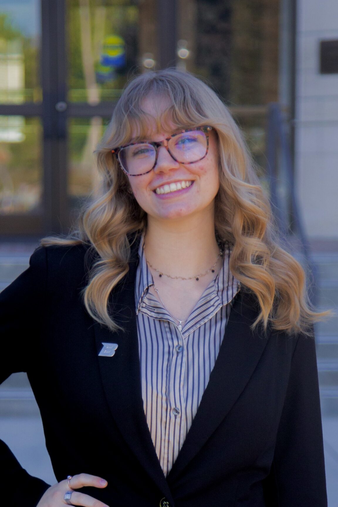 Mia Hoetker stands in front of glass doors, smiling