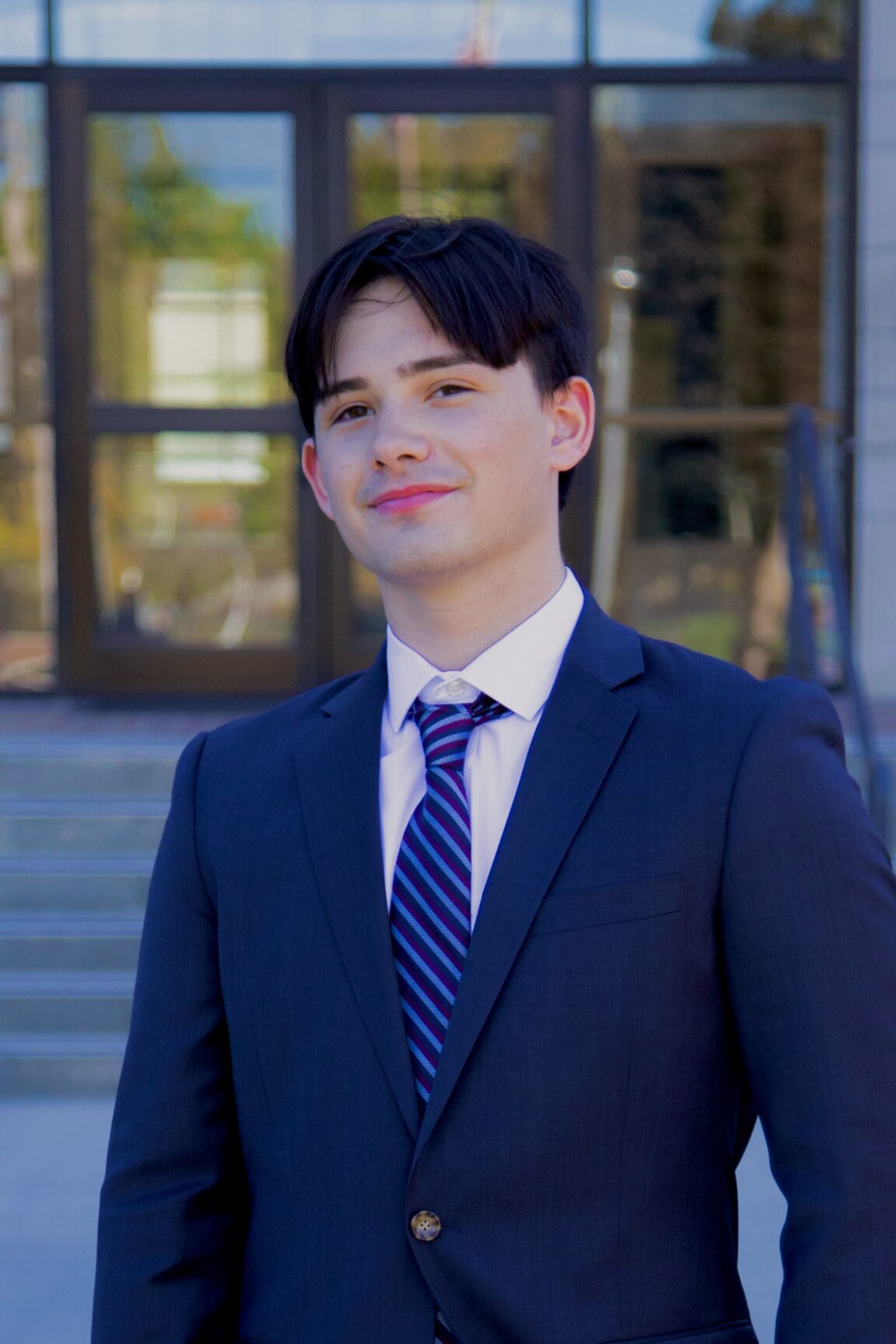 Ryan Maloney stands in front of glass doors, smiling