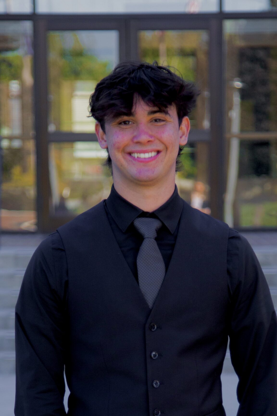 Ryan Torres stands on front of glass doors smiling