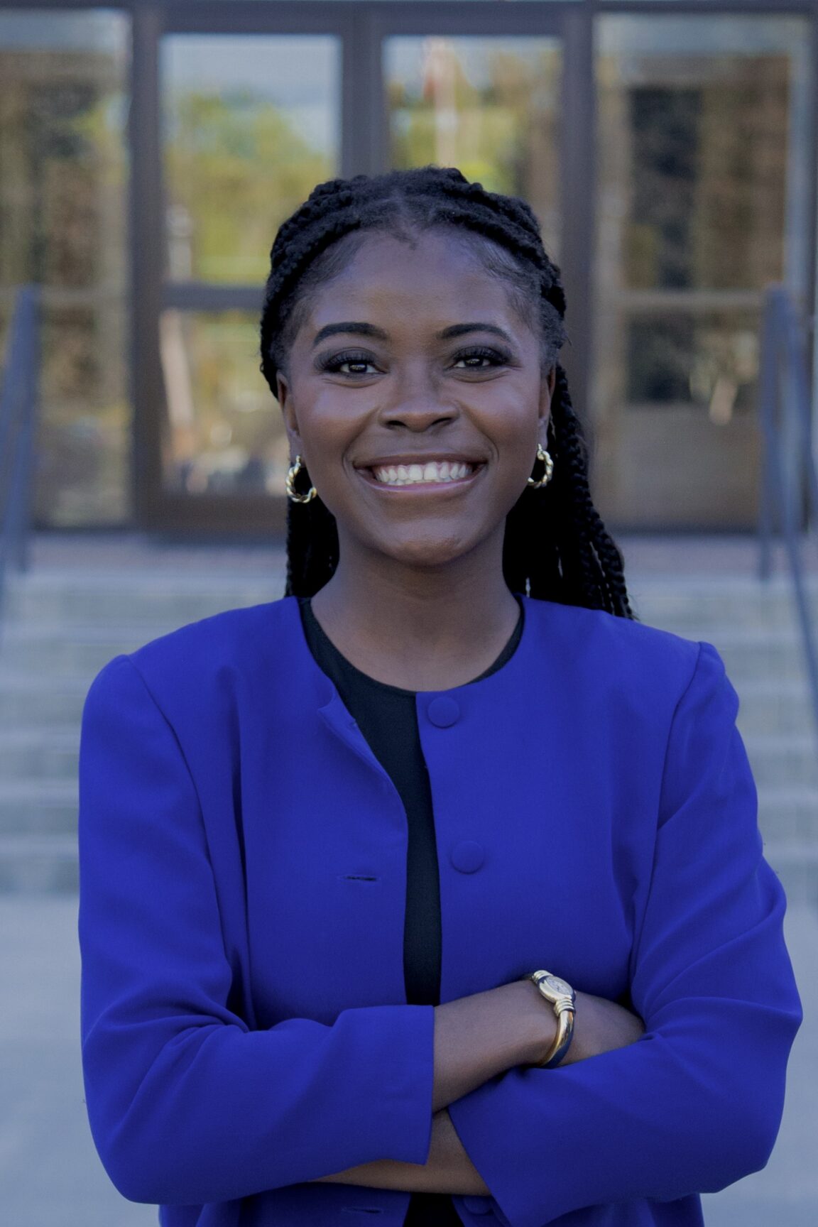 Tryphene Bulape Mishambo stands in front of glass doors, smiling