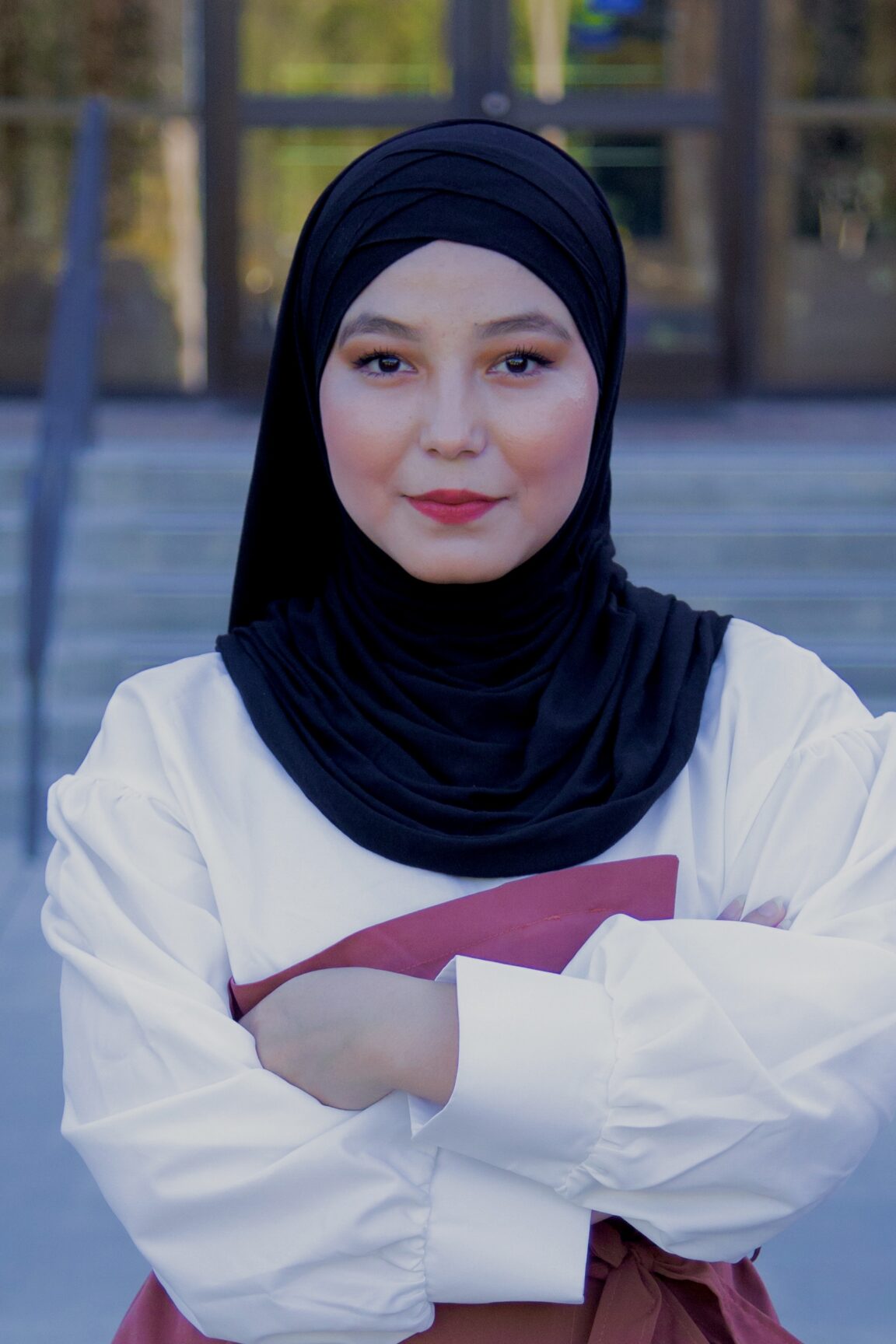 Zhara Chamanshah stands in front of glass doors, smiling