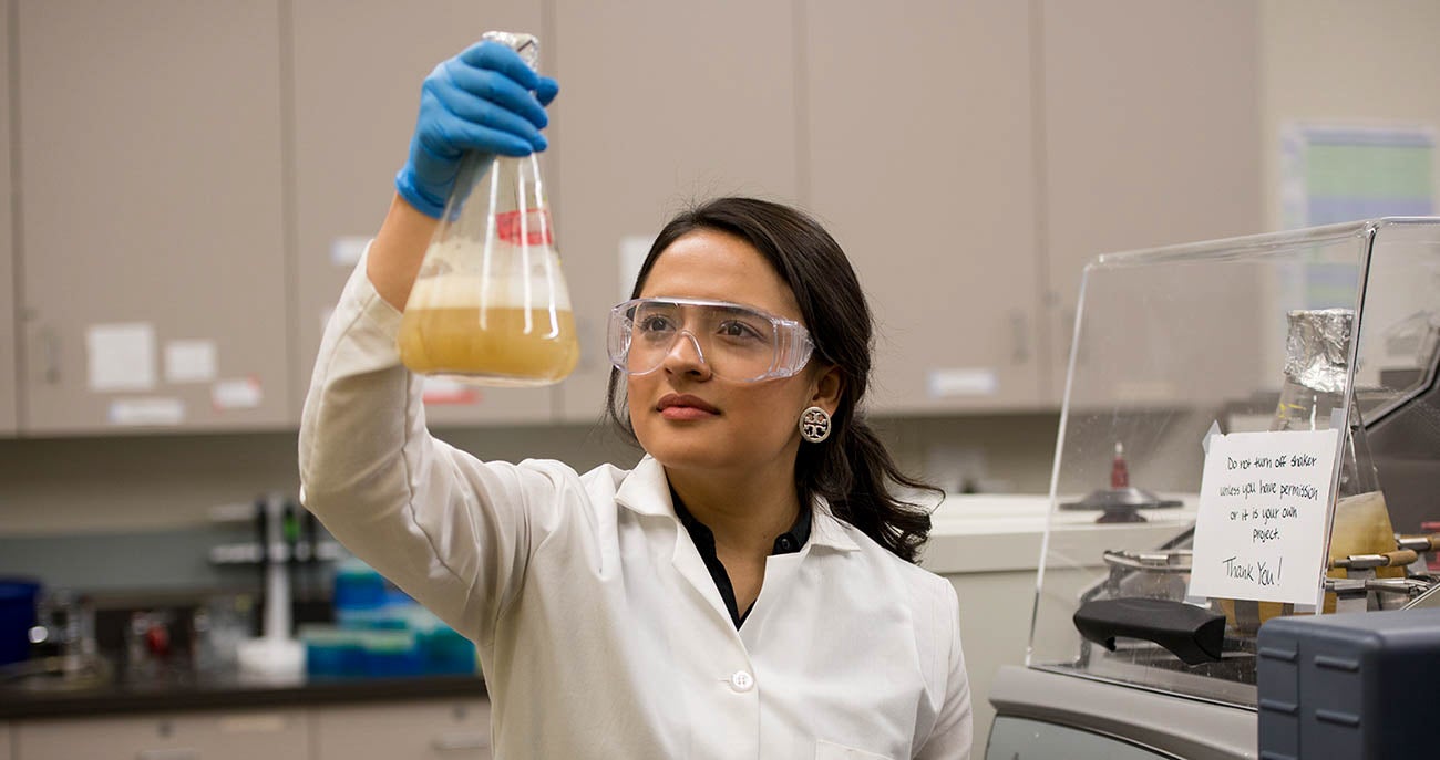 student raises beaker in lab