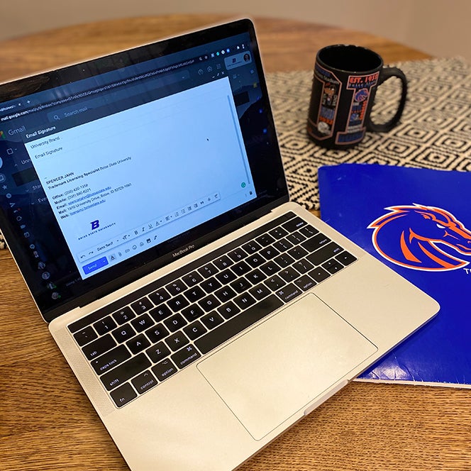 A computer, coffee mug and folder on a desk 