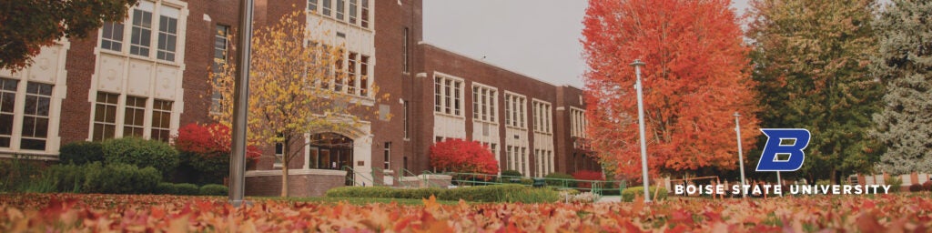 Cropped image of Administration building with the quad covered in colorful fall leaves.