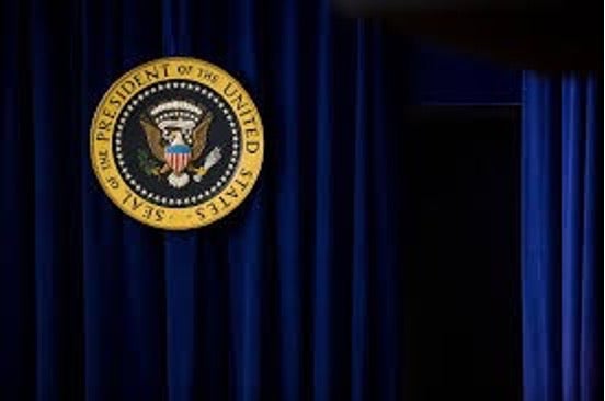 The presidential seal with blue curtains in background