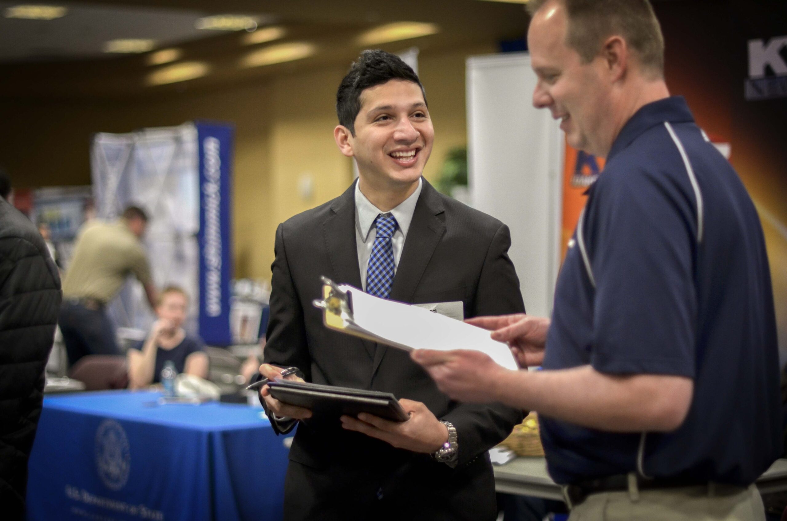 Student wearing a suit talking with an employer at a career fair