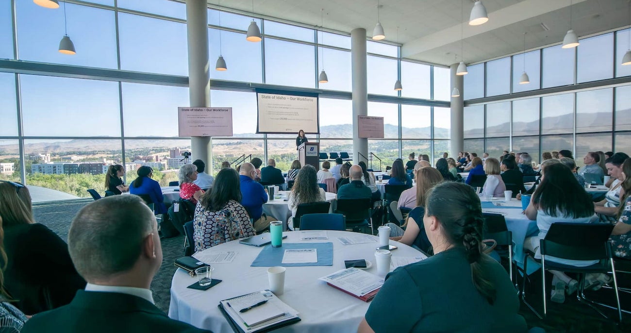 Employers and university representatives at the Idaho Statewide Experiential Learning Summit. Wide angle view of the room with the keynote speaker on stage.