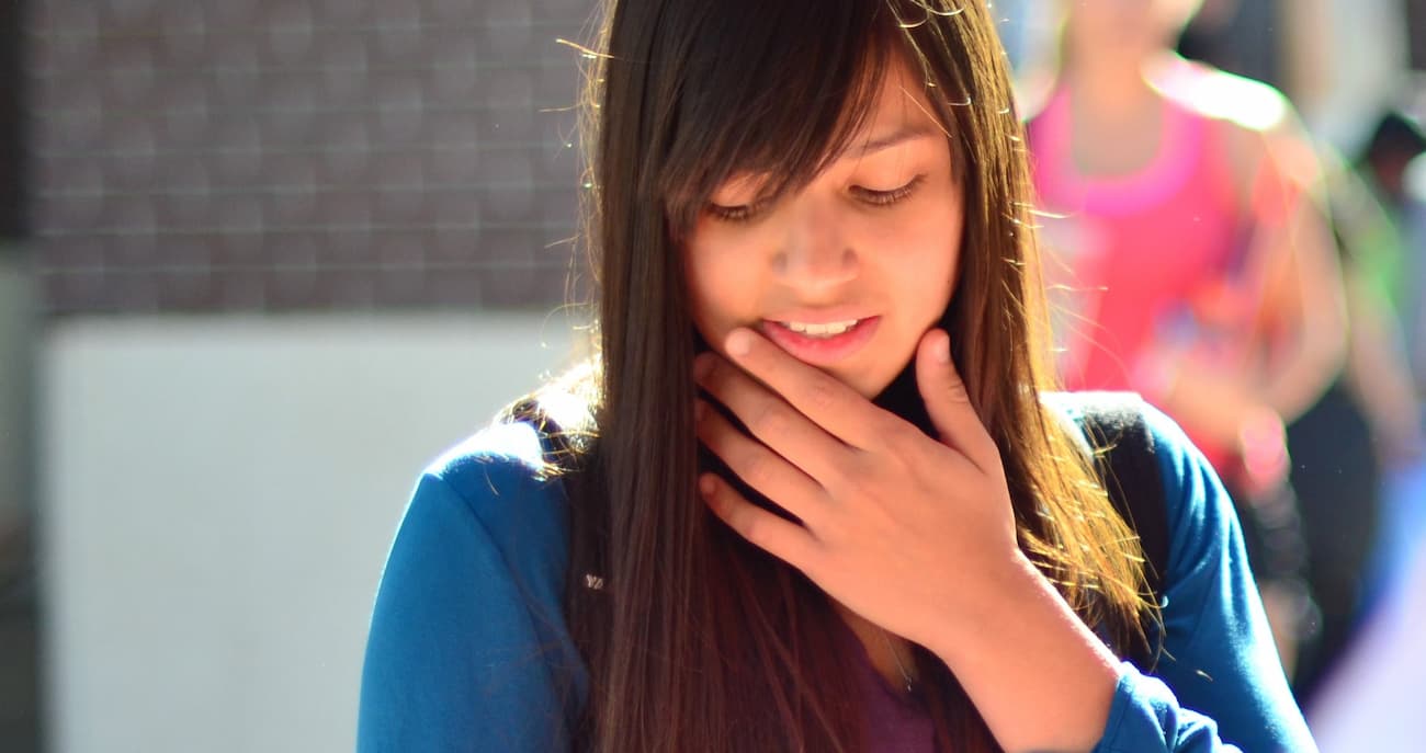 Student looking down with their hand on their chin like they are contemplating something