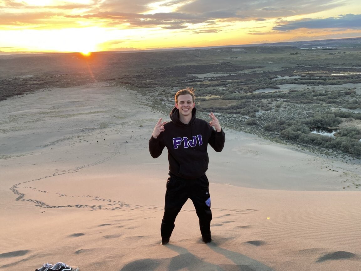 Matthew Lorentz standing atop a sand dune