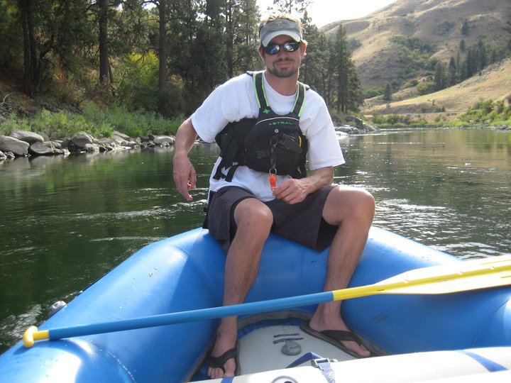 Chris Pajak sitting on the edge of a raft in a river