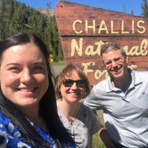 Owen McDougal, Jenny Weaver, and their graduate student Mia van Rheede van Oudtshoorn stand in front of the Challis National Forest Sign