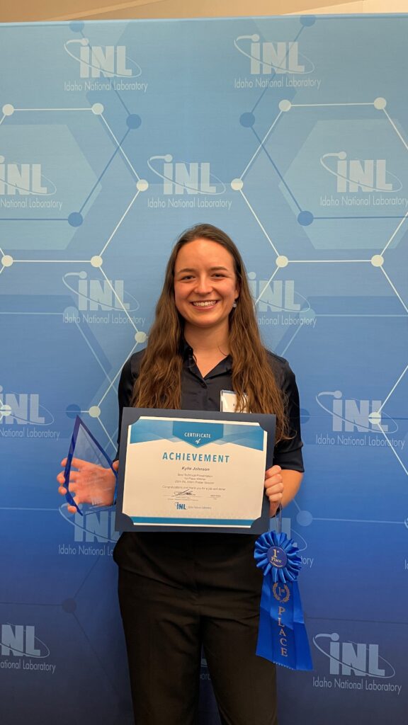 Photo of Kylie Johnson holding an award certificate for 1st place in Best Technical Presentation from the INL