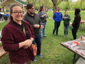 Photo of students standing in the park next to a picnic table