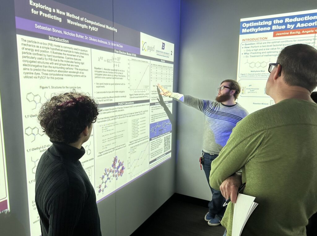 Photo of Sebastian Bones and NIcolas Buhler explaining their PChem poster to Brian McClain