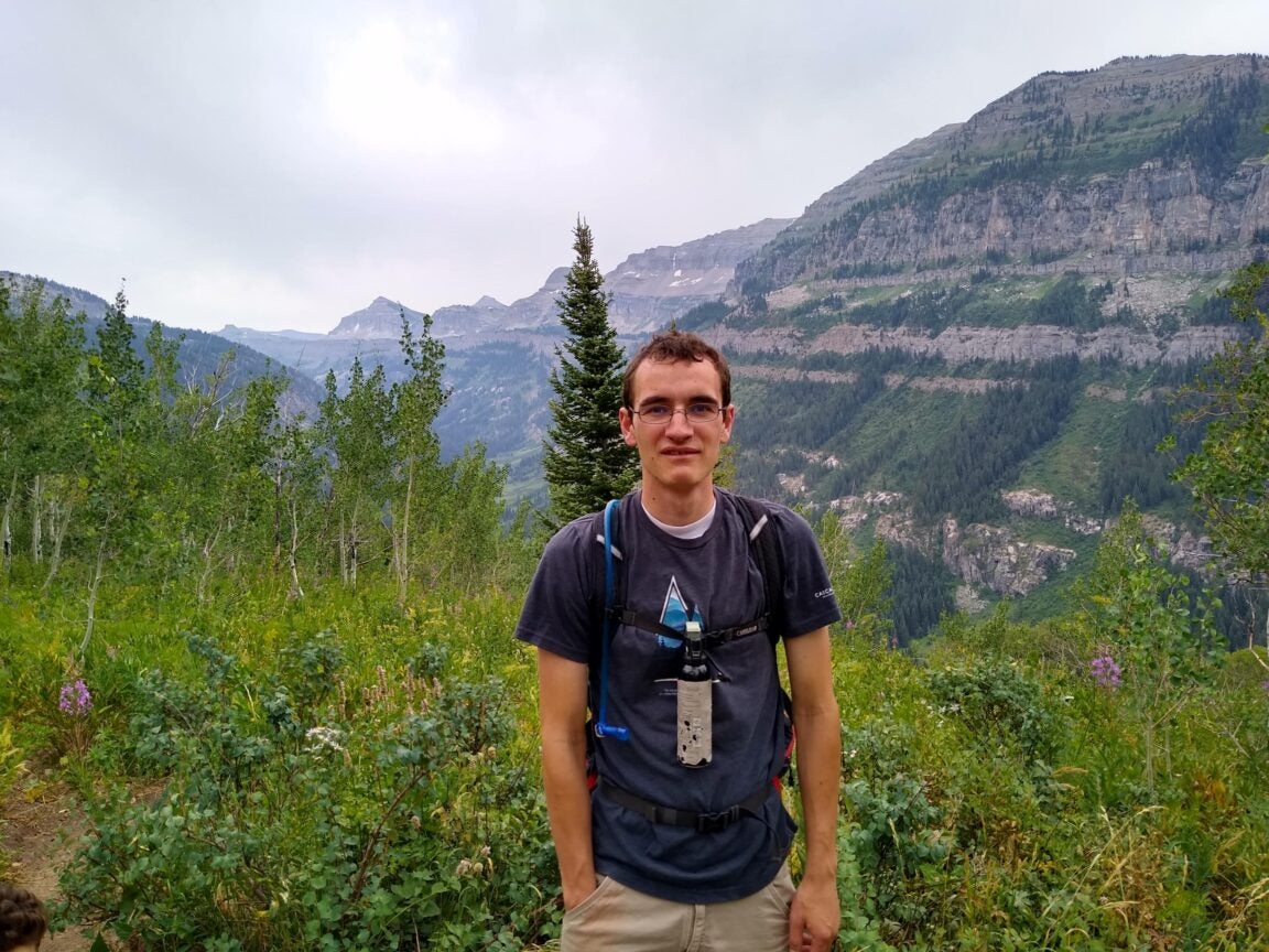 Photo of Kaden Shaw standing outside with mountains in the background