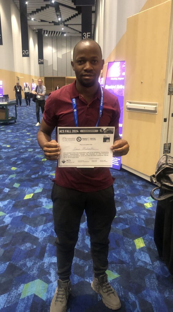 Photo of Denis Mulumba holding his Best Oral Presentation award certificate