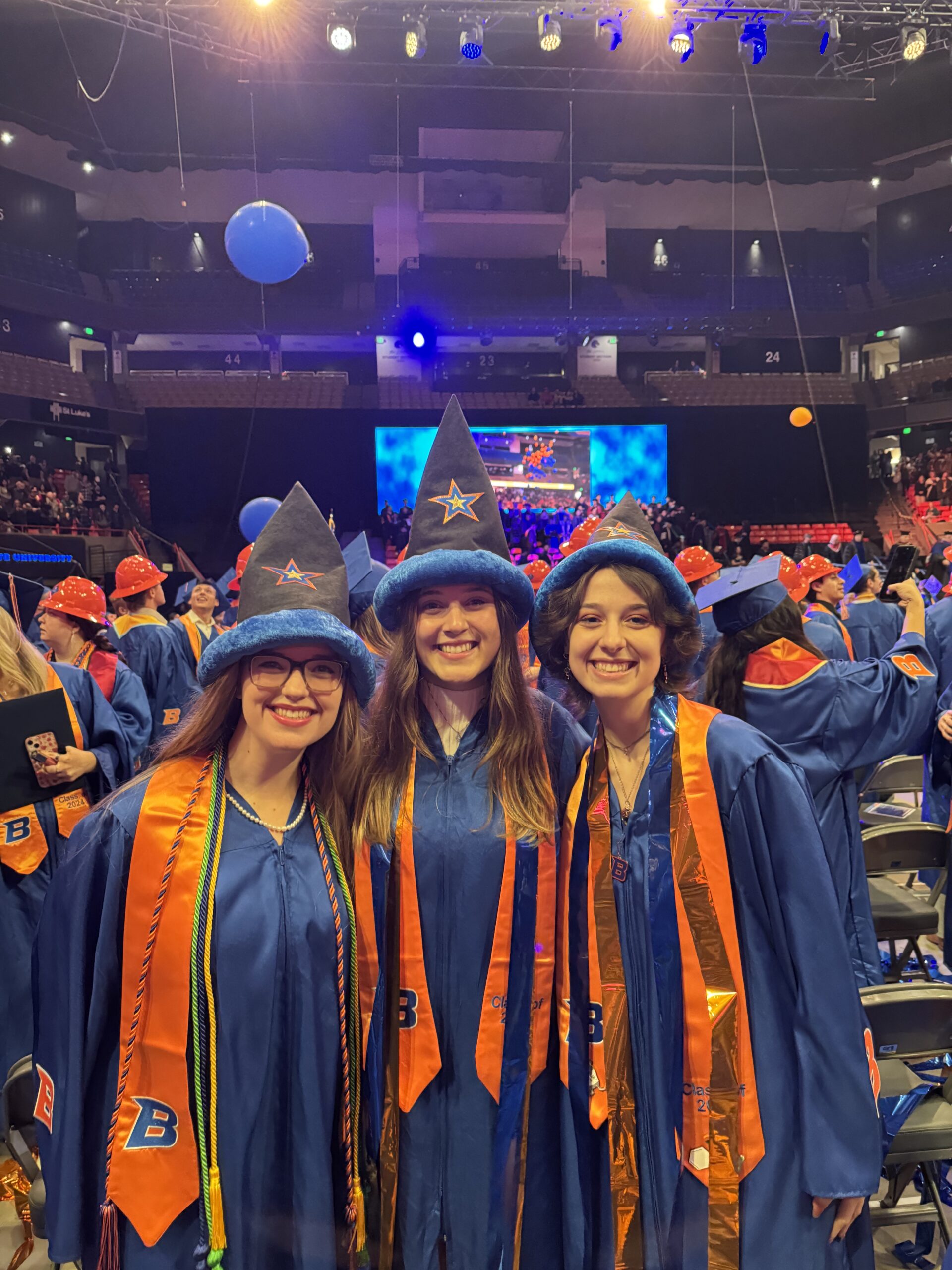 Kathryn Pierson, Molly Gage and Kelso Hinrichs wearing their wizard hats and graduation gowns at the Fall 2024 commencement