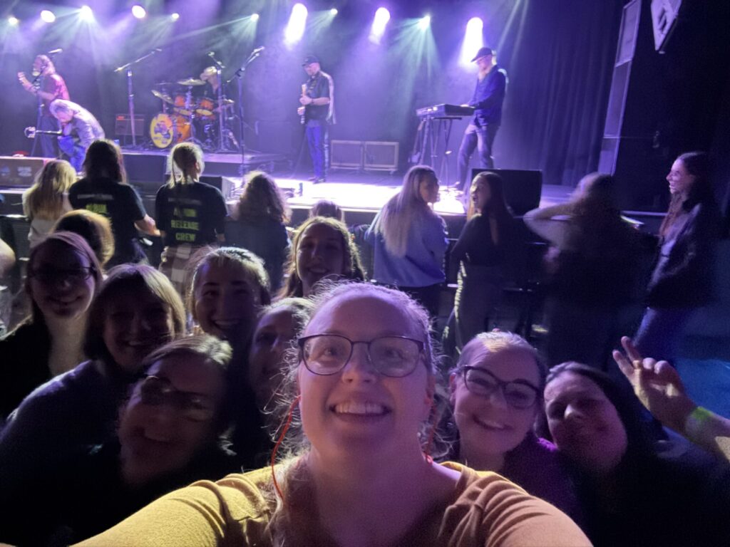 A group of department students and staff standing in front of the stage with Chris Saunders in the background