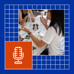 A group of people is engaged in a discussion at a casual dining setting. A woman in a white t-shirt and glasses is animatedly speaking, gesturing with her hands while others at the table listen. The table is filled with items such as a water bottle, glasses, and a phone. The image is overlaid with a blue grid design, incorporating a rounded section that frames the scene. In the lower-left corner, an orange square features a minimalist white microphone icon, symbolizing speaking, pitching ideas, or podcasting.